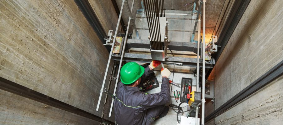 Elevator installation and maintenance. lift machinist worker adjusting elevator mechanism with spanners in shaft hoistway